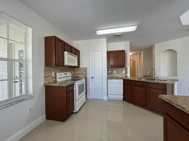 a large kitchen with stainless steel appliances granite countertop a stove a sink and a refrigerator