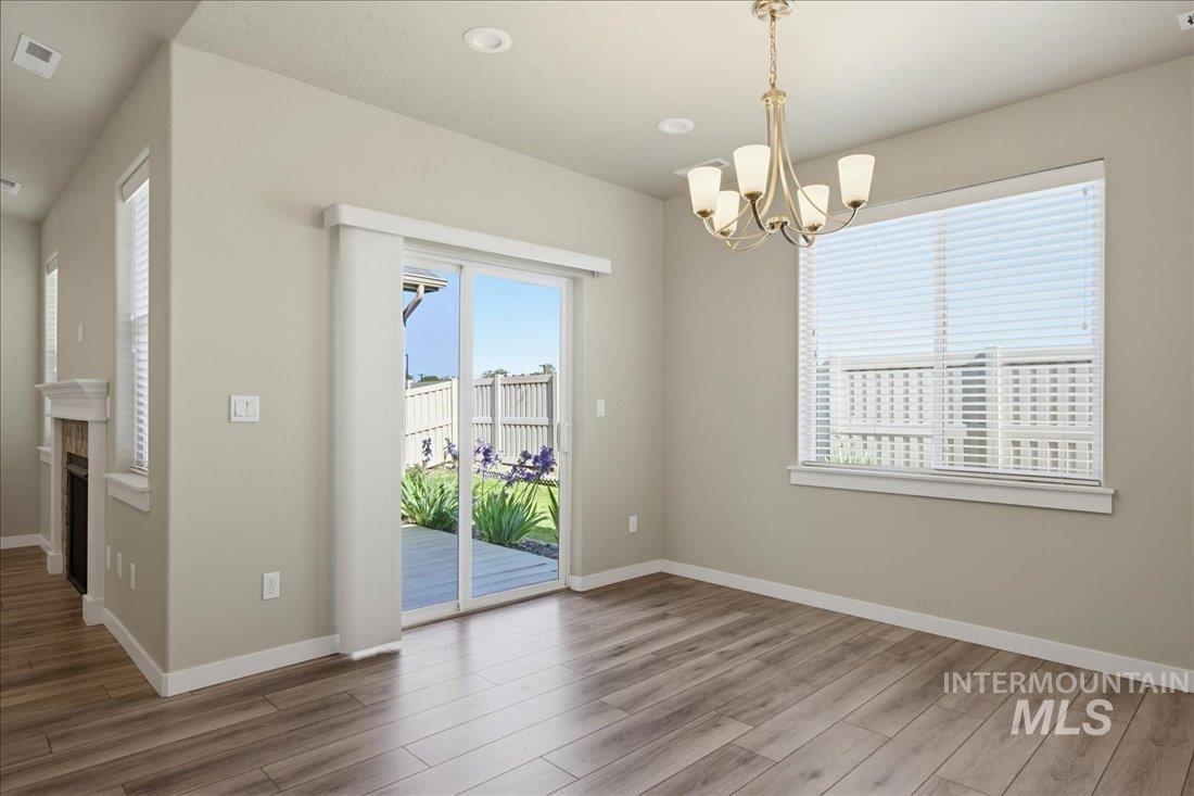 12460 West Azure Street Boise, ID 83713 - Photo 13 of 34 Open living area featuring wood-finish flooring, a contemporary chandelier, a sliding glass door opening to an outdoor deck, and a window with blinds