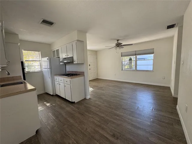 a living room with stainless steel appliances furniture and a wooden floor