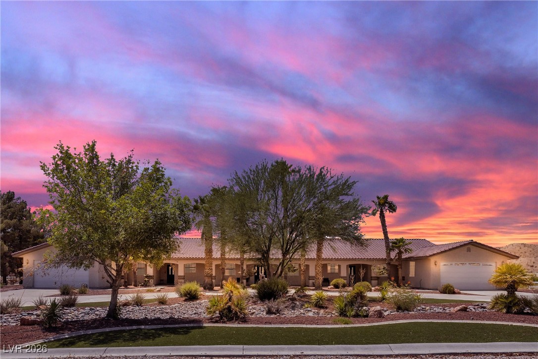 Ranch-style home featuring driveway, a tile roof, a garage, and stucco siding