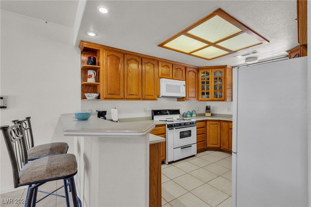 825 West Ryan Avenue Overton, NV 89040 - Photo 24 of 88 Kitchen with white appliances, a peninsula, light tile patterned floors, brown cabinets, and recessed lighting