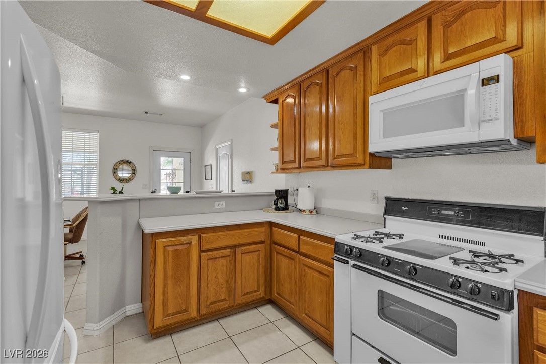 825 West Ryan Avenue Overton, NV 89040 - Photo 25 of 88 Kitchen with white appliances, a peninsula, brown cabinetry, a textured ceiling, and recessed lighting