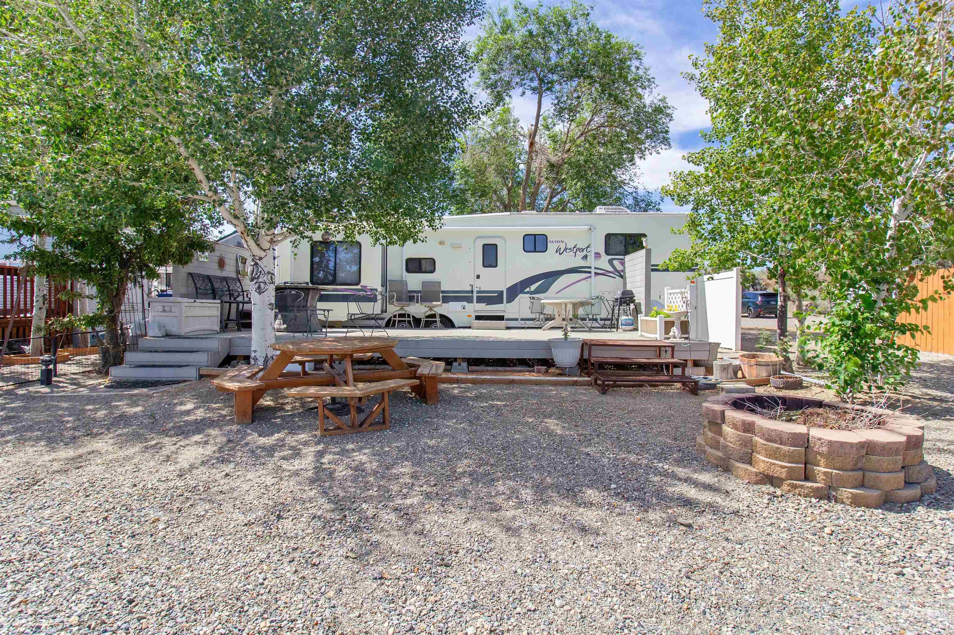 106 West Magic Road Shoshone, ID 83352 - Photo 1 of 45 Spacious gravel lot featuring mature trees, a multi-level deck, and a built-in stone fire pit