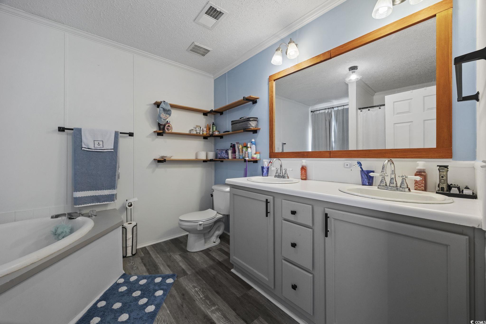 944 Pine Thicket Street Myrtle Beach, SC 29577 - Photo 13 of 27 Bathroom with a textured ceiling, double vanity, a garden tub, dark wood finished floors, and curtained shower