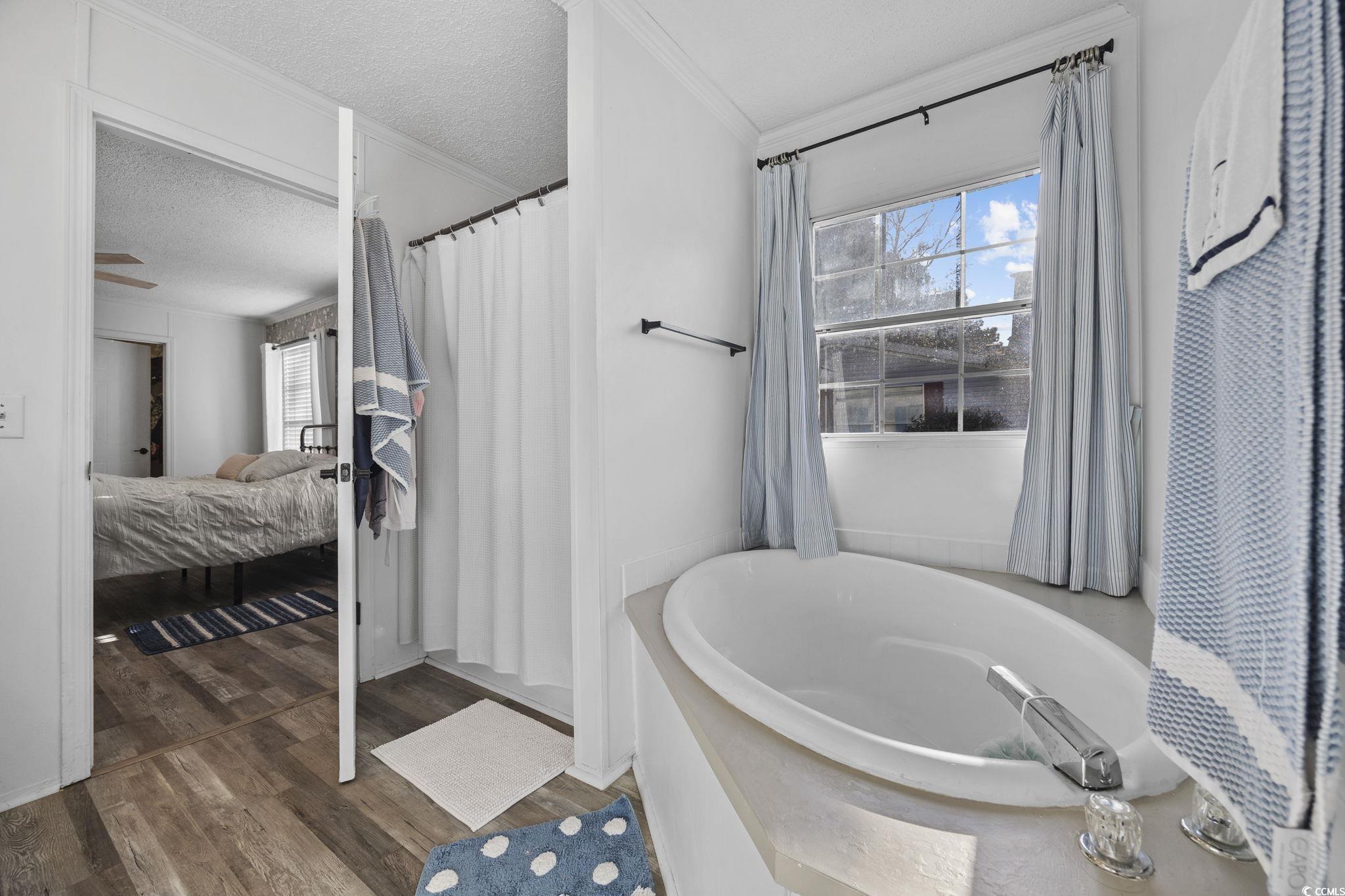 944 Pine Thicket Street Myrtle Beach, SC 29577 - Photo 15 of 27 Ensuite bathroom featuring healthy amount of natural light, a garden tub, ornamental molding, dark wood-type flooring, and a textured ceiling