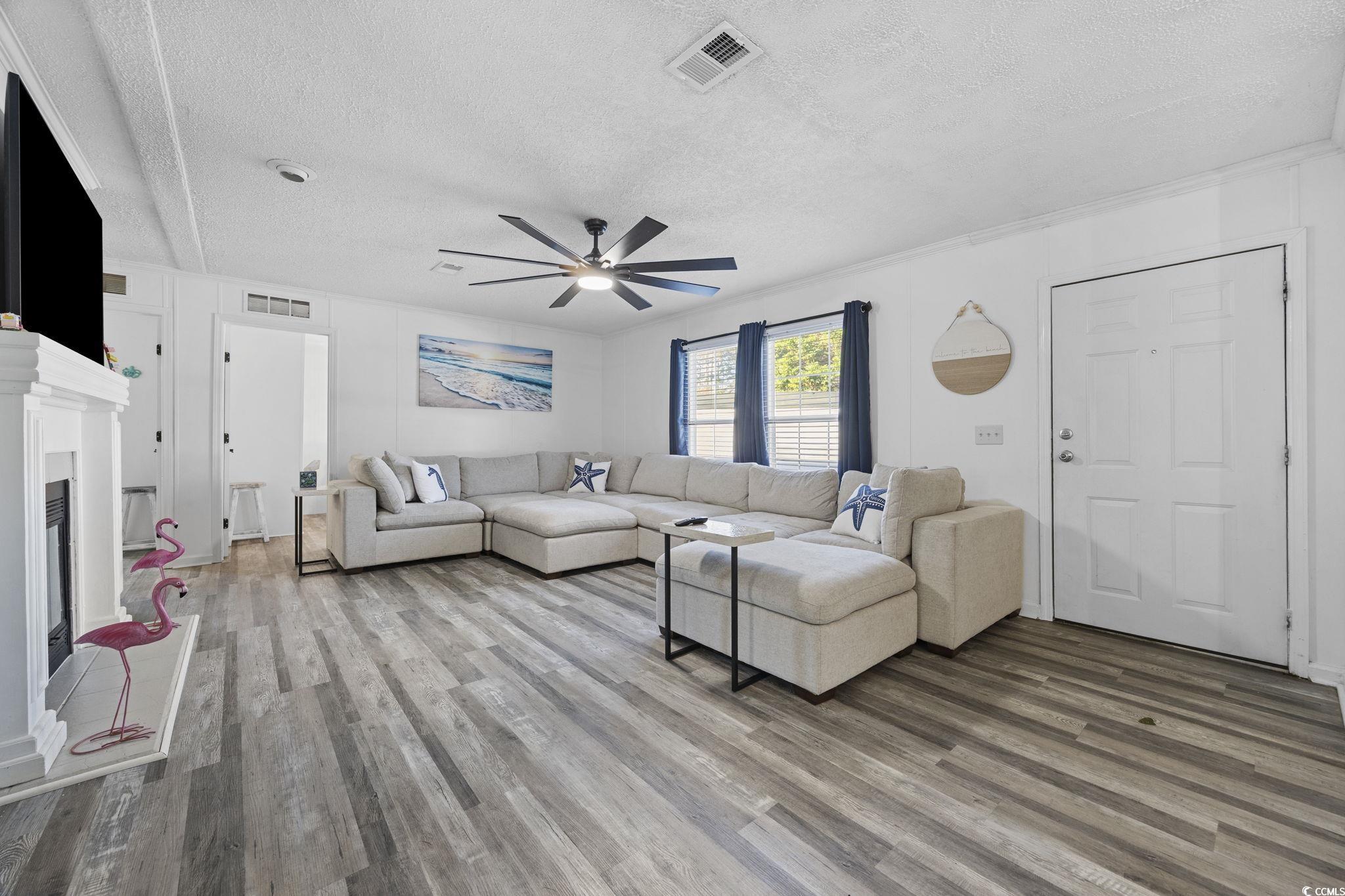 944 Pine Thicket Street Myrtle Beach, SC 29577 - Photo 3 of 27 Living room with a textured ceiling, wood finished floors, a glass covered fireplace, and ceiling fan