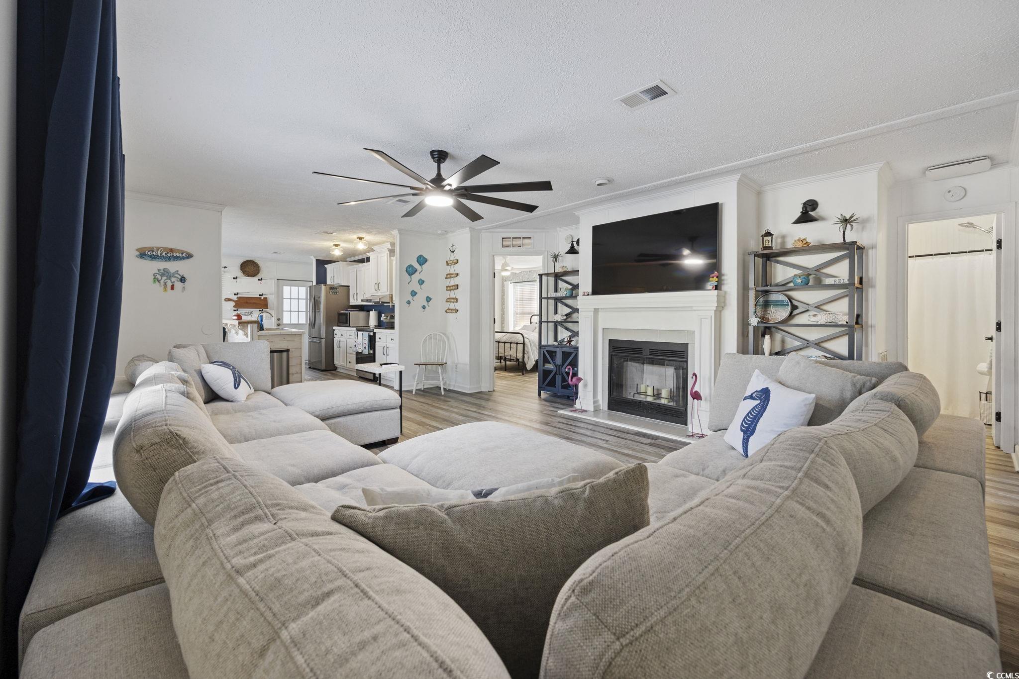 944 Pine Thicket Street Myrtle Beach, SC 29577 - Photo 5 of 27 Living area with a glass covered fireplace, crown molding, wood finished floors, ceiling fan, and a textured ceiling