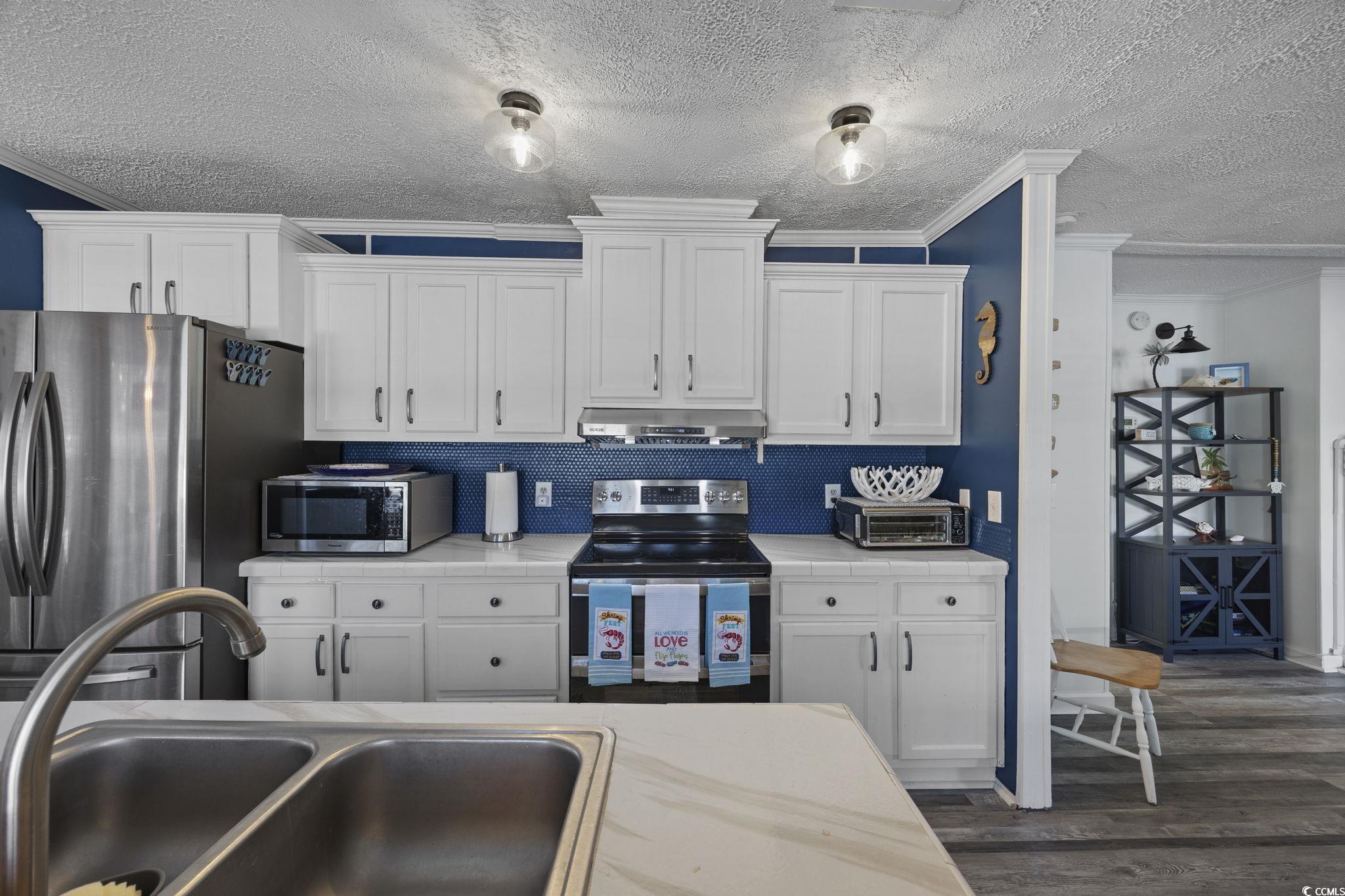944 Pine Thicket Street Myrtle Beach, SC 29577 - Photo 9 of 27 Kitchen featuring ornamental molding, appliances with stainless steel finishes, white cabinetry, a textured ceiling, and dark wood-style flooring