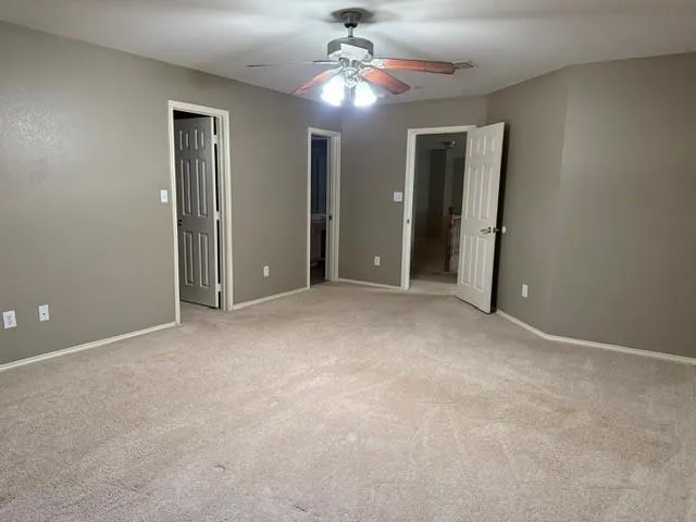 en empty room with windows and chandelier fan