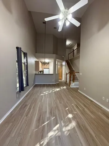 a view of a livingroom with wooden floor a ceiling fan and staircase