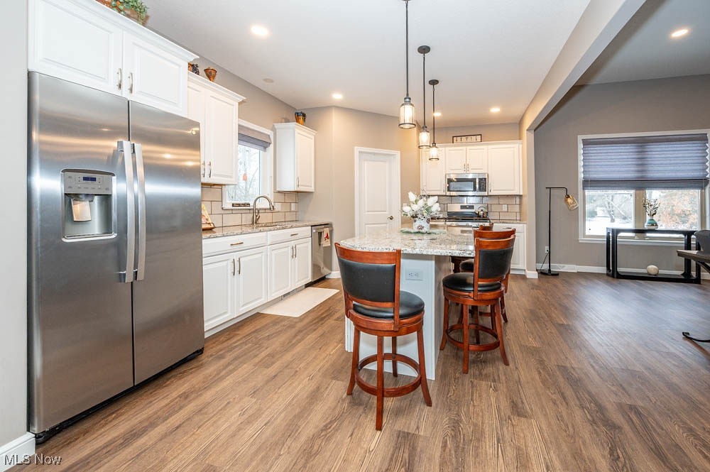 6580 Abbey Road North Canfield, OH 44406 - Photo 12 of 32 Kitchen with stainless steel appliances, light stone countertops, decorative light fixtures, a center island, and white cabinetry