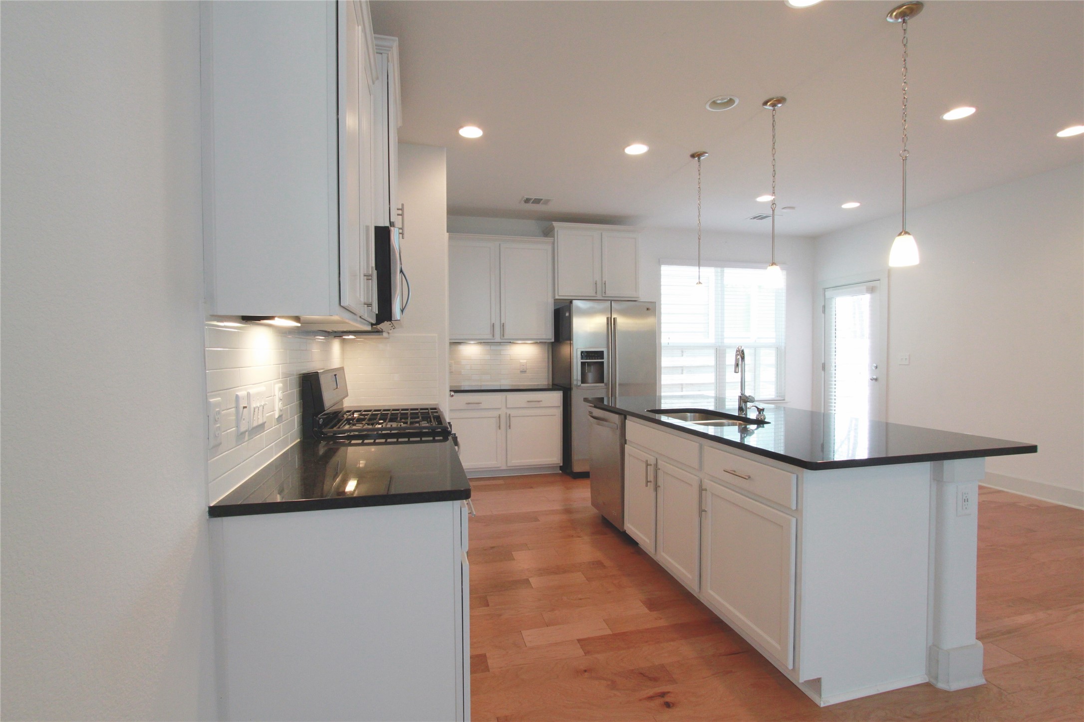 1507 Homespun Road Austin, TX 78745 - Photo 11 of 35 Contemporary kitchen featuring white cabinetry, black countertops, stainless steel appliances, and a central island with a sink