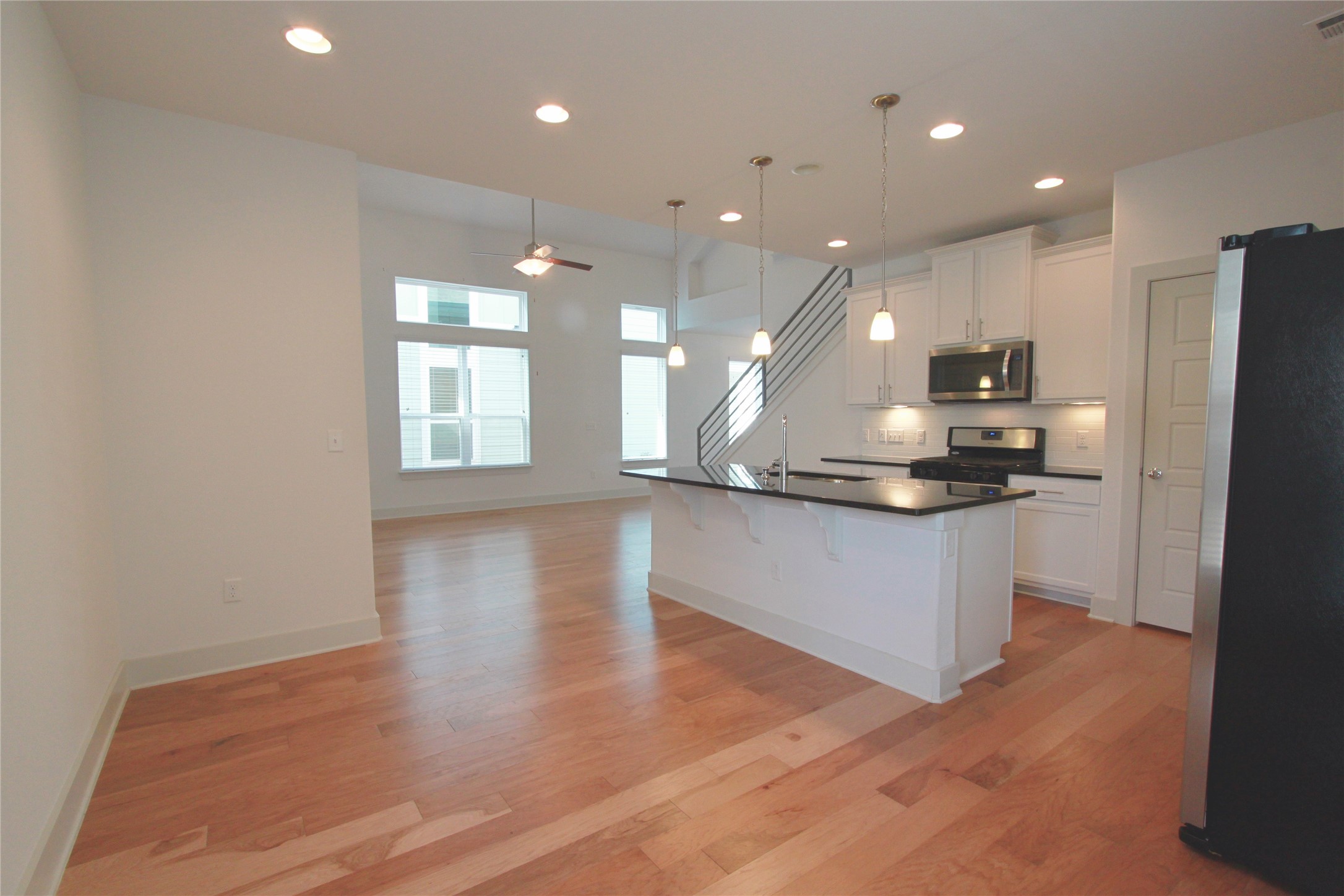1507 Homespun Road Austin, TX 78745 - Photo 13 of 35 Open-concept living space featuring wood-finish flooring, recessed lighting, and a contemporary kitchen with white cabinetry and a black countertop island
