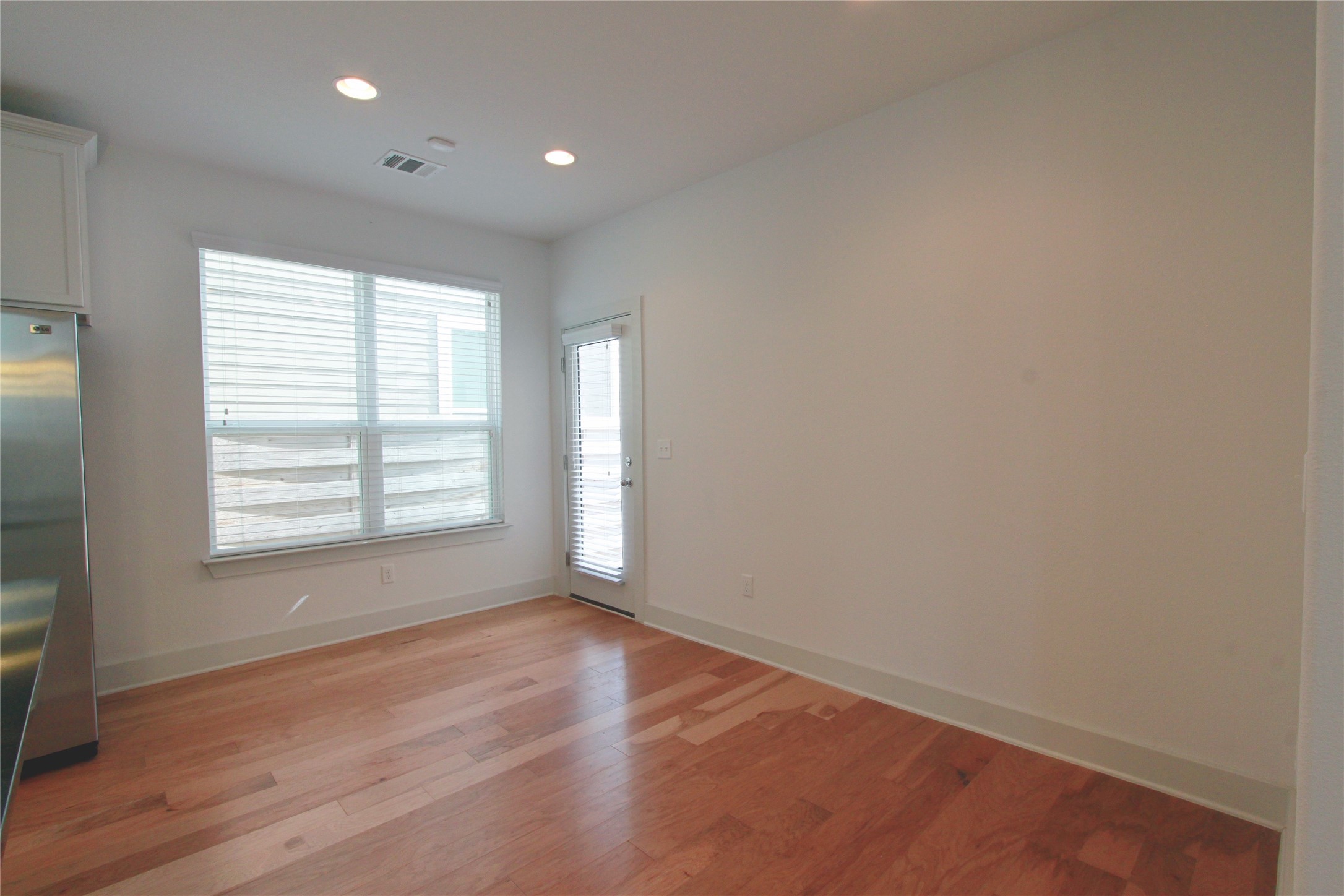 1507 Homespun Road Austin, TX 78745 - Photo 14 of 35 Bright interior space featuring wood-finish flooring, recessed lighting, a large window with blinds, and a glass-paneled door