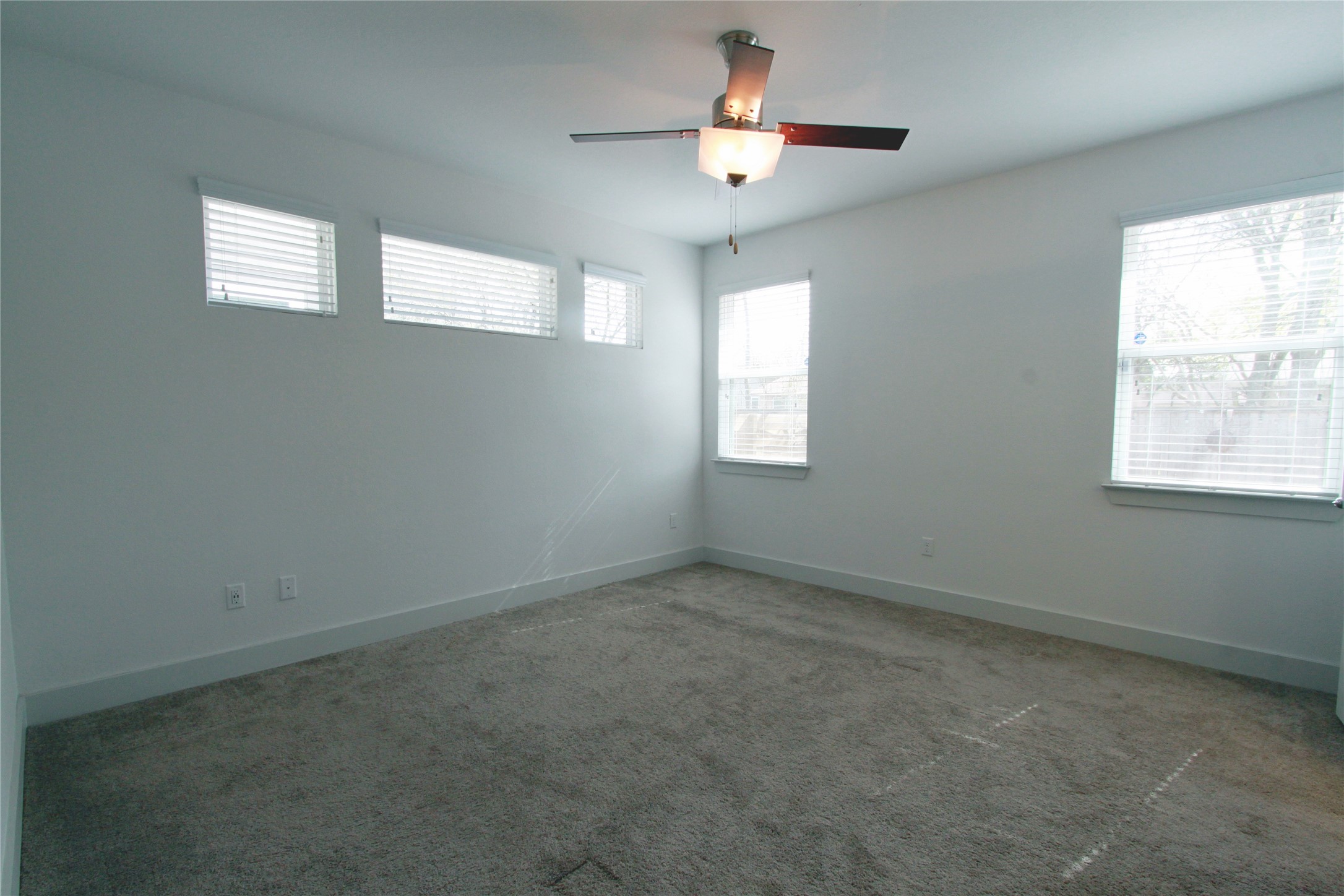 1507 Homespun Road Austin, TX 78745 - Photo 15 of 35 Spacious interior featuring neutral carpeting, white wall finishes, multiple windows with blinds, and a contemporary ceiling fan with lighting