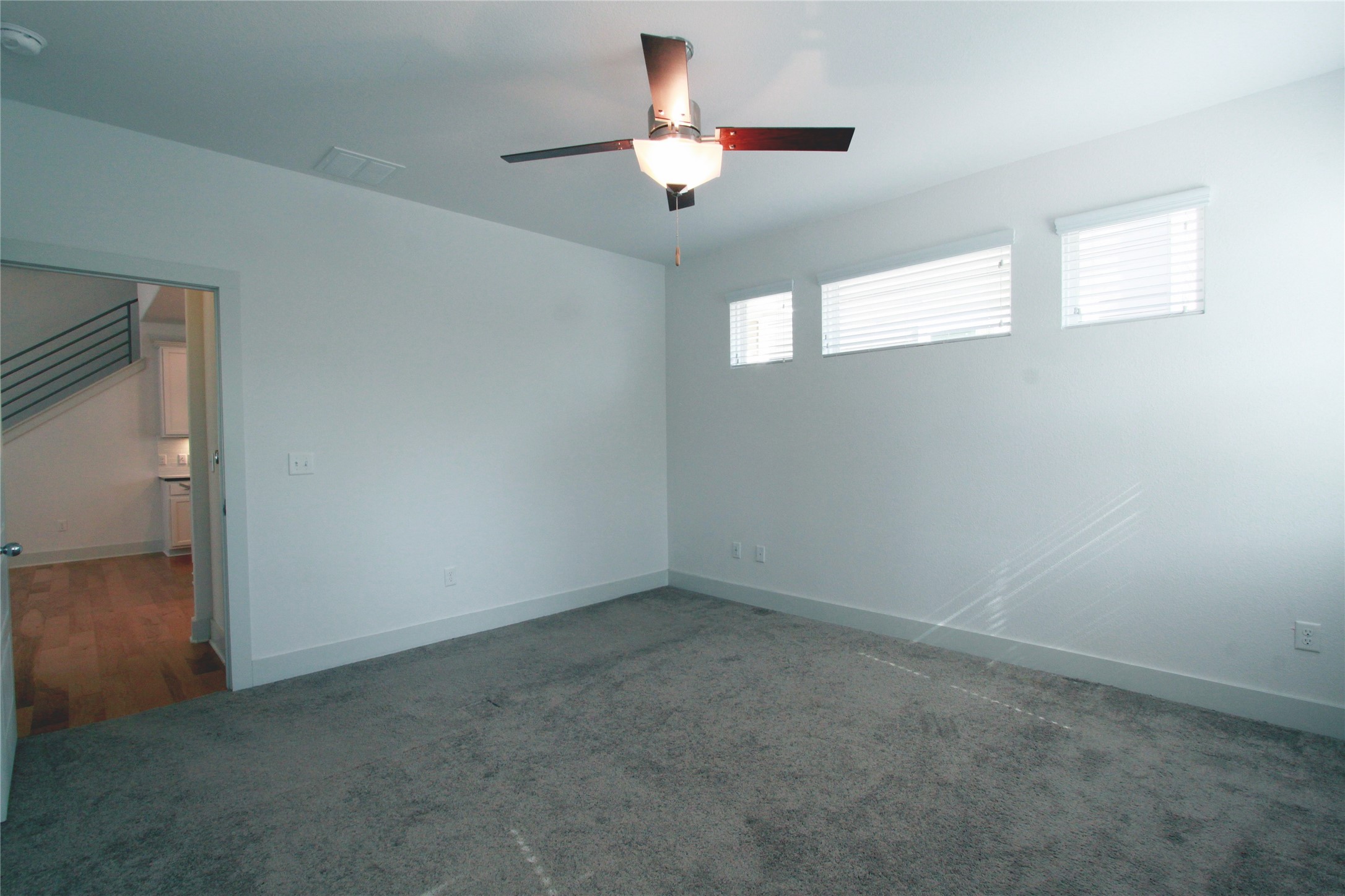 1507 Homespun Road Austin, TX 78745 - Photo 17 of 35 Spacious room featuring gray carpeting, white walls, a ceiling fan with integrated lighting, and three horizontal windows with white blinds