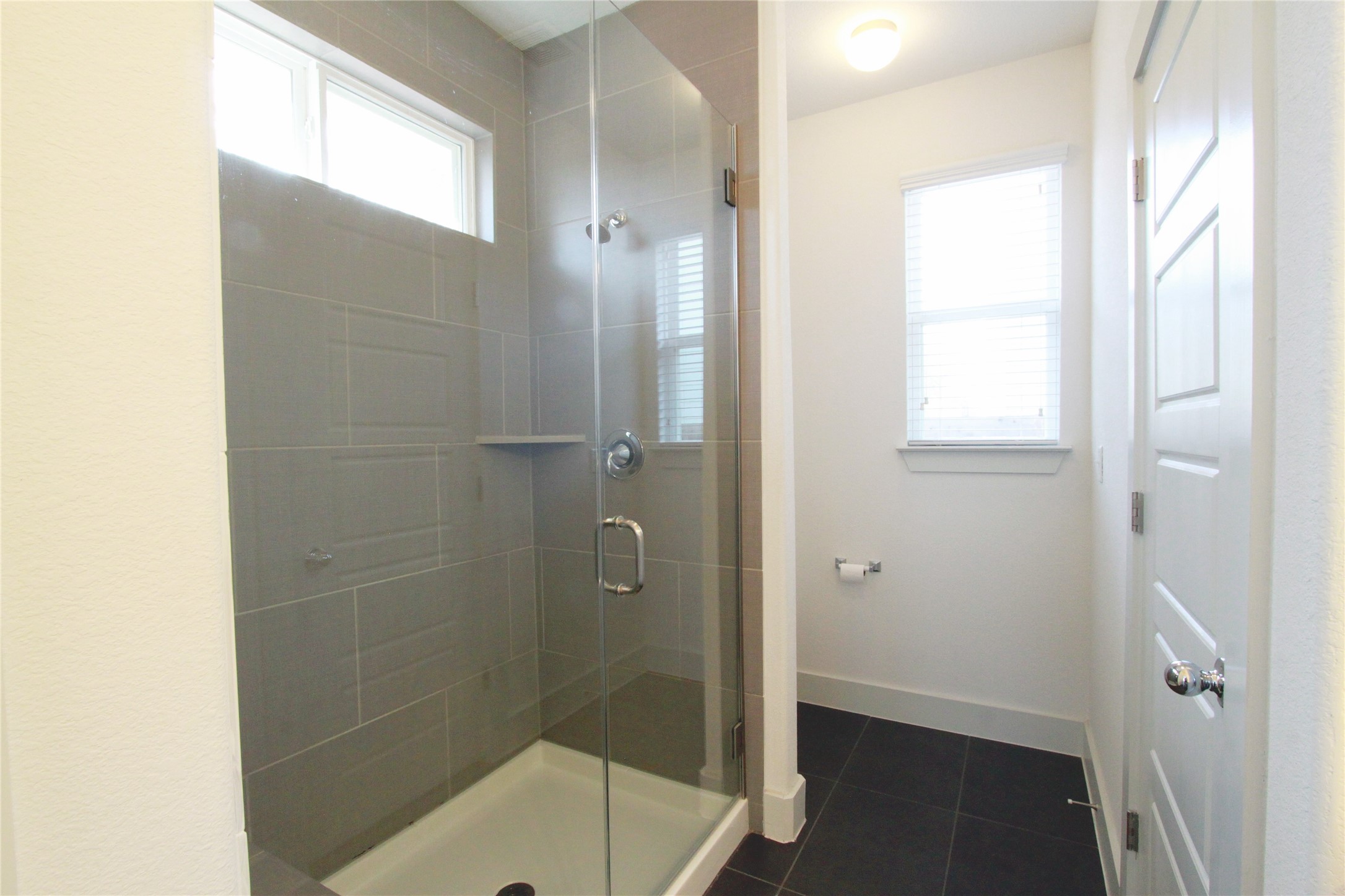 1507 Homespun Road Austin, TX 78745 - Photo 19 of 35 Shower enclosure featuring a glass door, grey tile surround, and built-in shelf