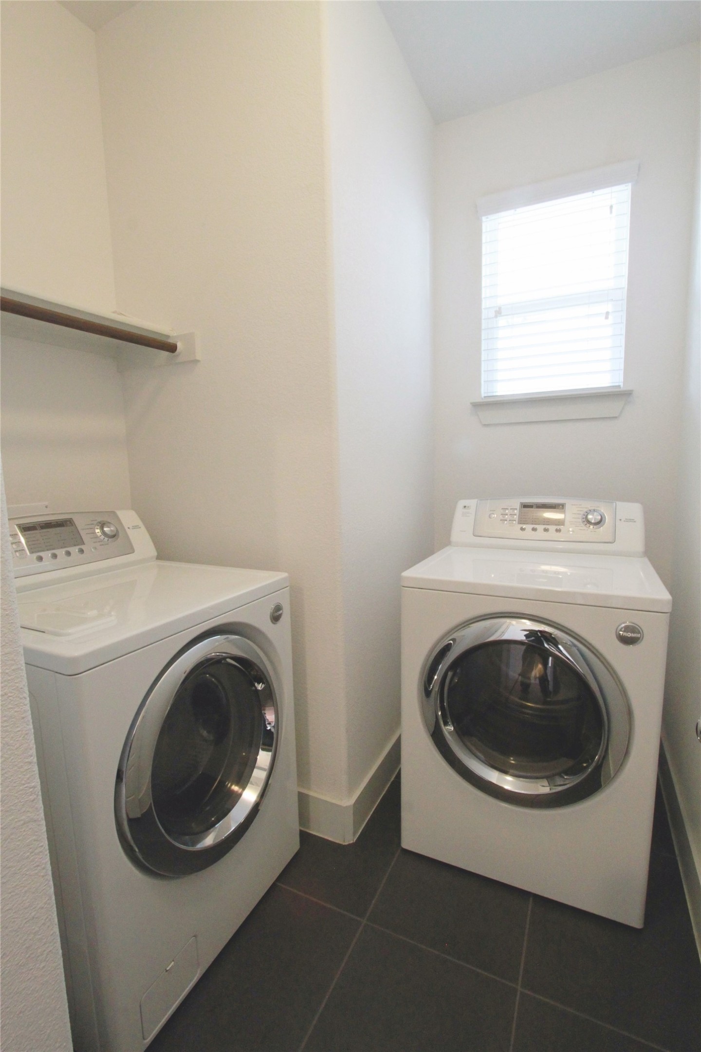 1507 Homespun Road Austin, TX 78745 - Photo 21 of 35 Utility area featuring dark tile flooring, a window with horizontal blinds, and a built-in shelving rod