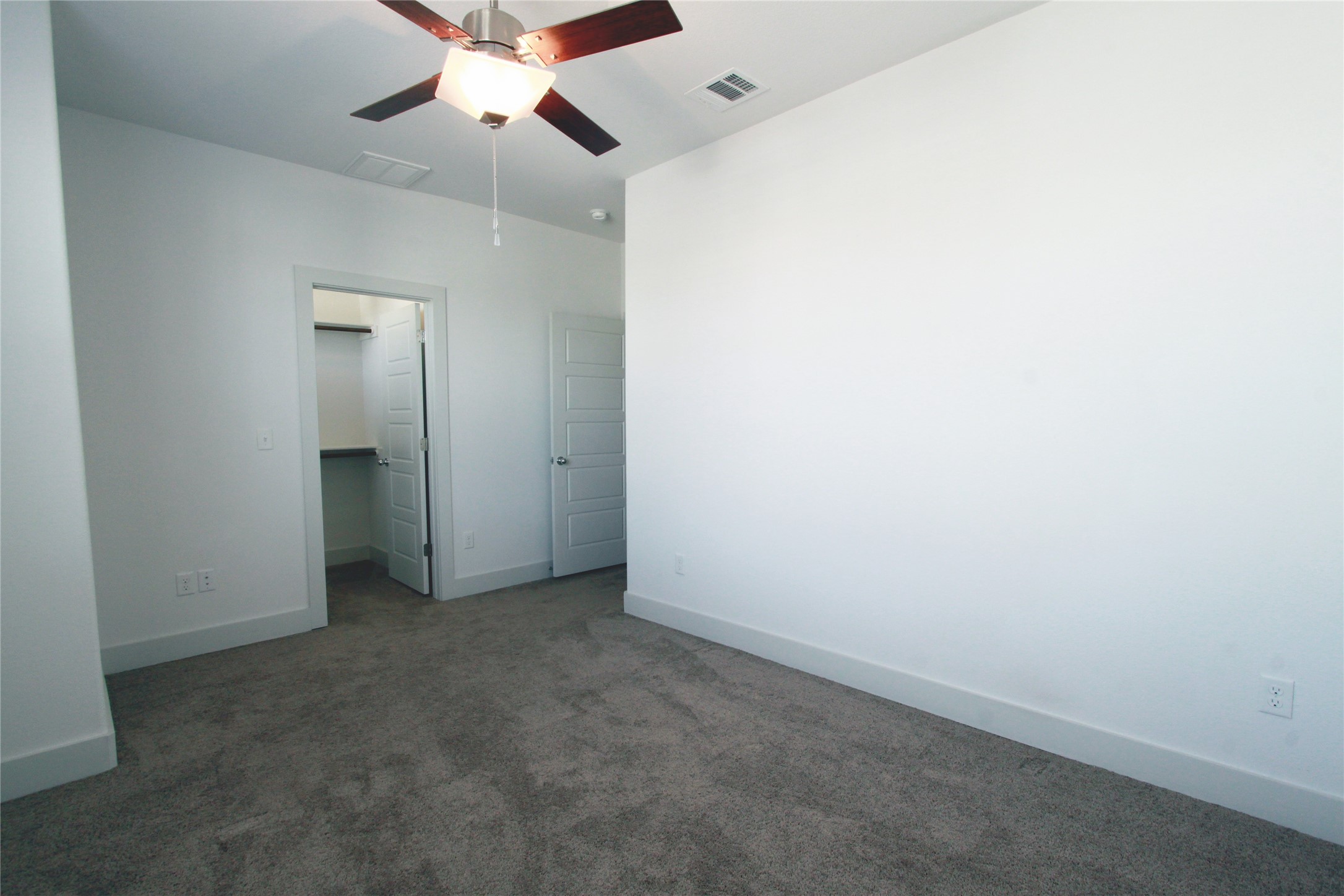 1507 Homespun Road Austin, TX 78745 - Photo 27 of 35 Carpeted room featuring a ceiling fan with light fixture, white walls, and a walk-in closet with shelving