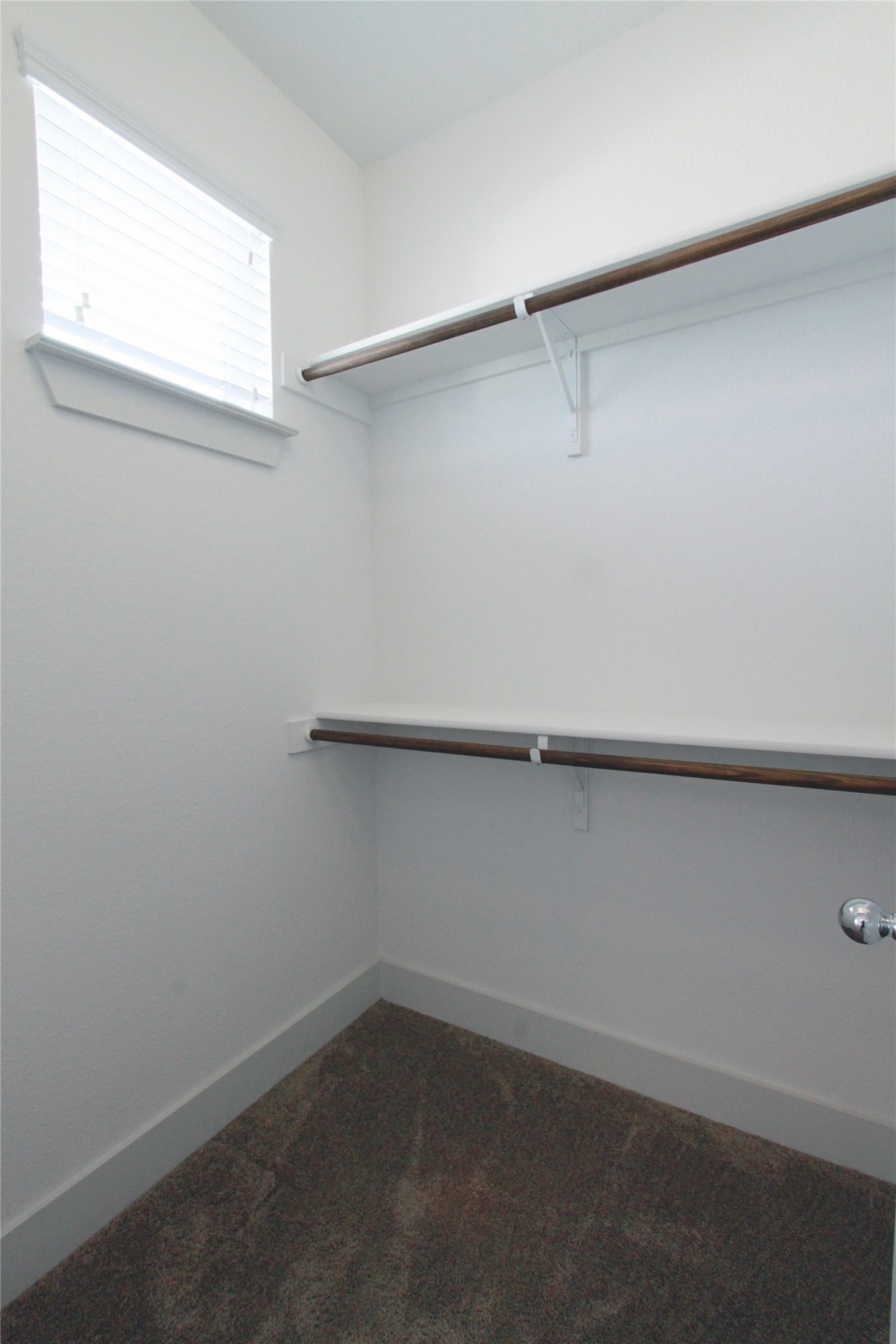 1507 Homespun Road Austin, TX 78745 - Photo 28 of 35 Walk-in closet featuring white walls, a small window with blinds, two levels of hanging rods, and dark gray carpet flooring
