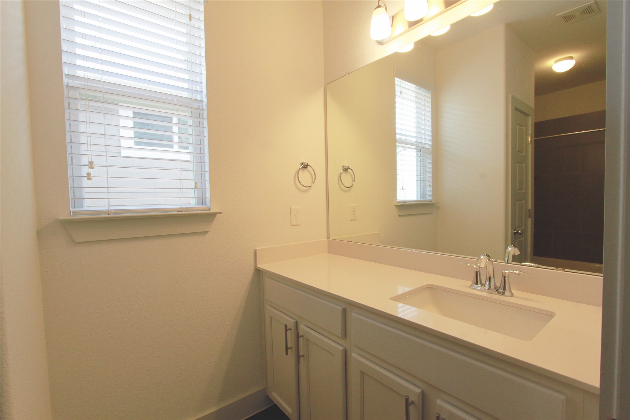 1507 Homespun Road Austin, TX 78745 - Photo 31 of 35 Bathroom vanity featuring an integrated sink, polished chrome faucet, and expansive mirror