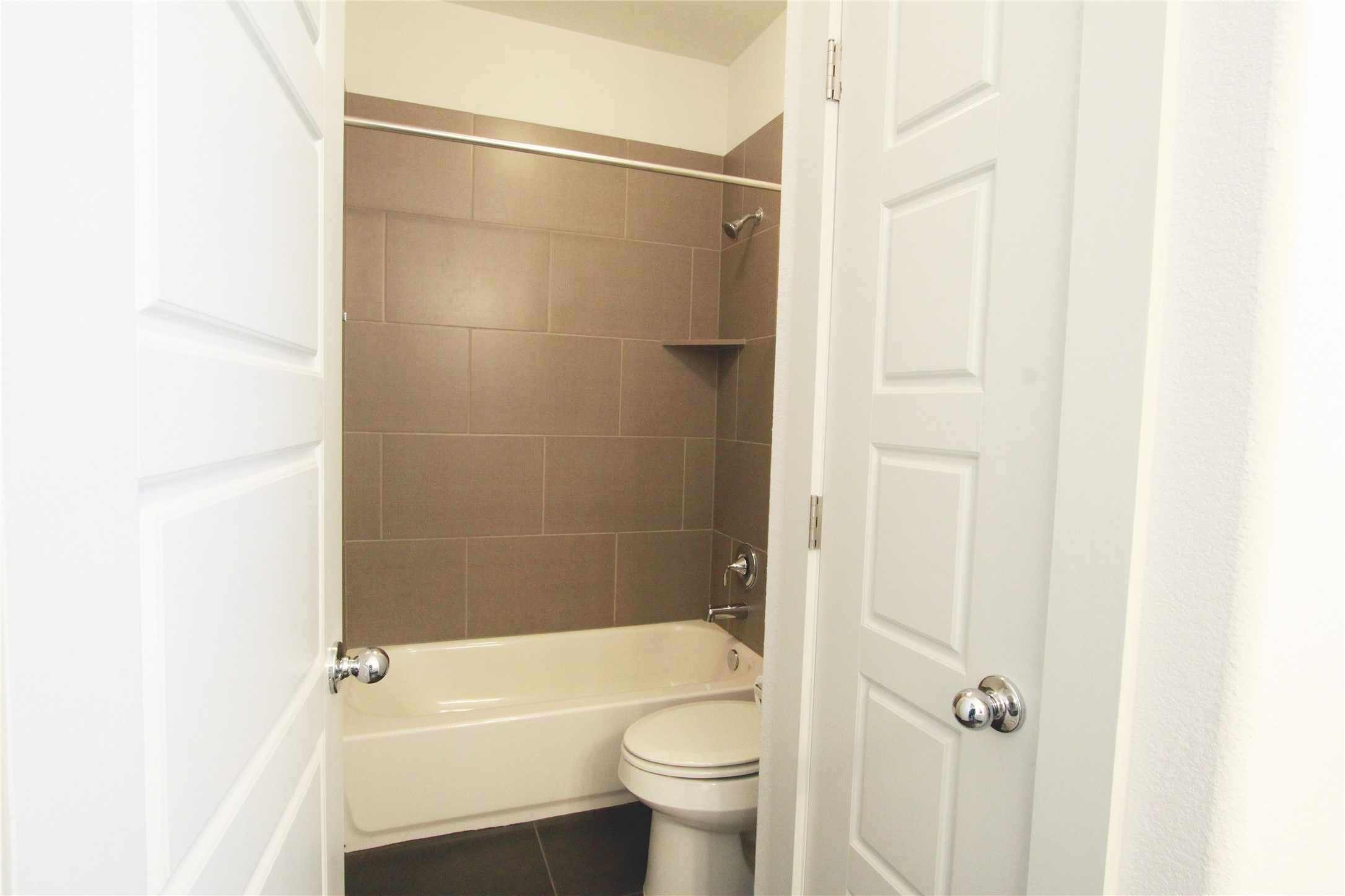 1507 Homespun Road Austin, TX 78745 - Photo 32 of 35 Bathroom featuring a white bathtub, toilet, and shower with horizontal brown tile work