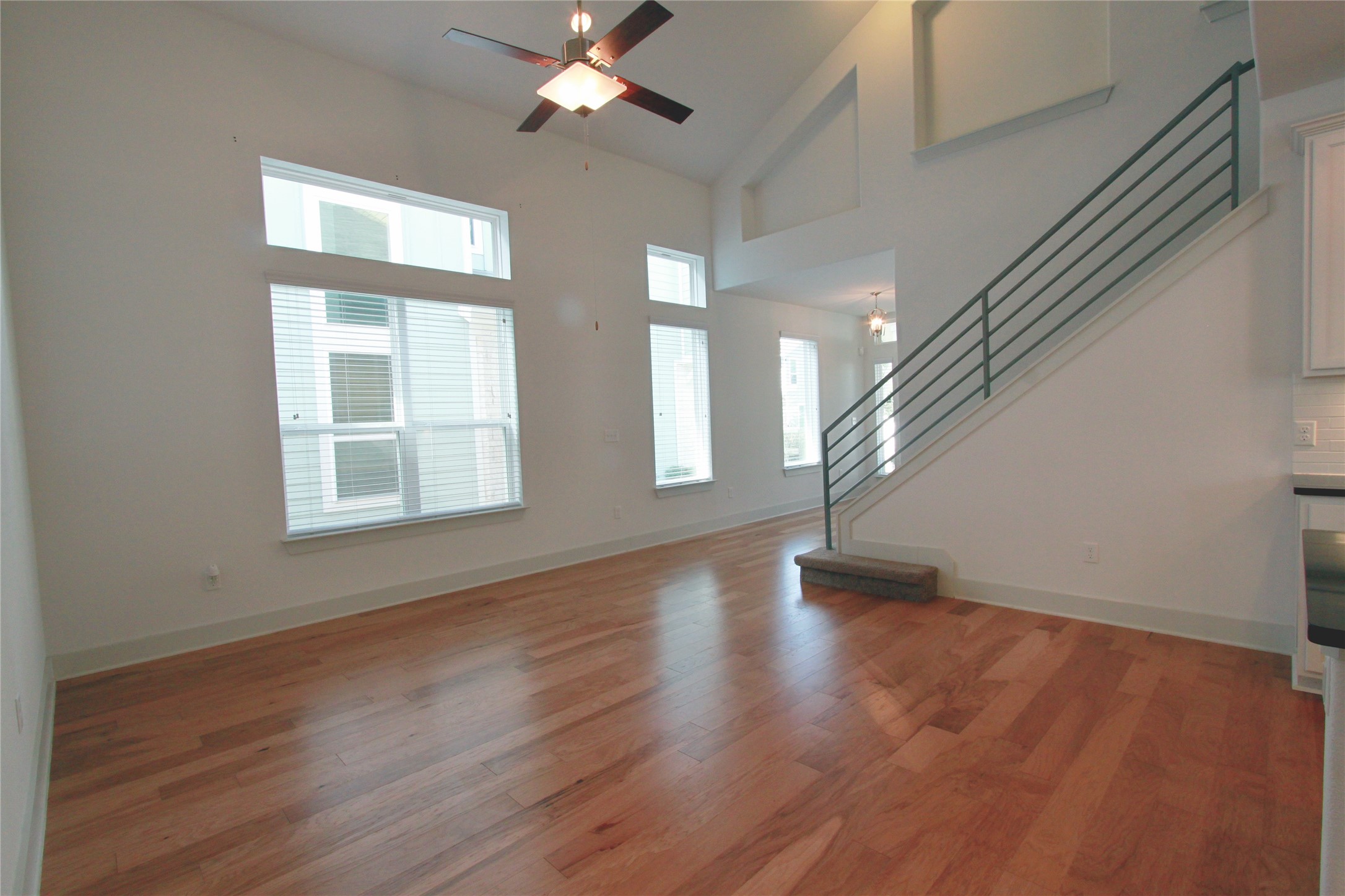 1507 Homespun Road Austin, TX 78745 - Photo 7 of 35 Spacious living area featuring high vaulted ceilings, multiple windows, wood-finish flooring, a contemporary staircase with metal railings, and a ceiling fan with integrated lighting
