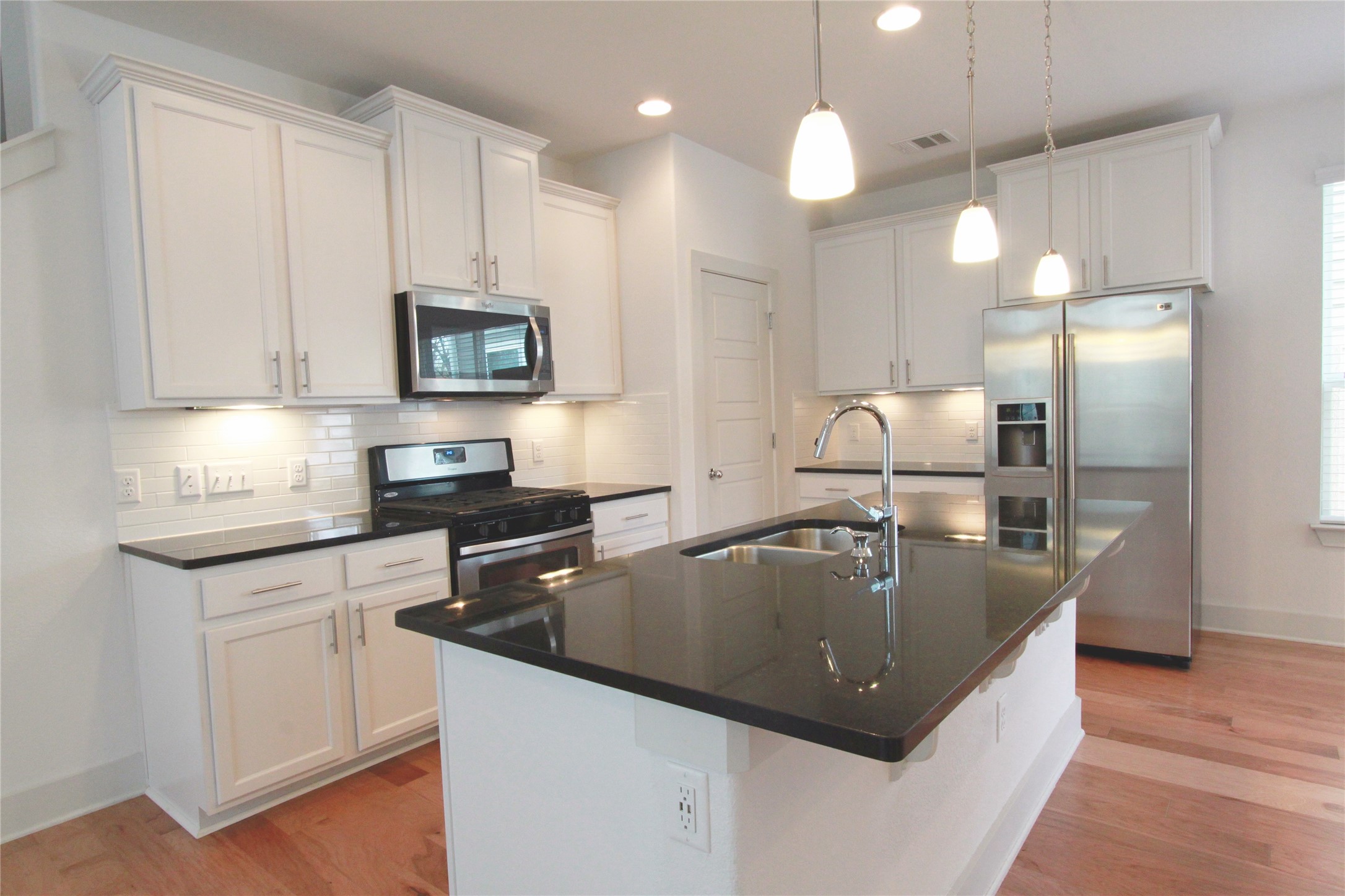 1507 Homespun Road Austin, TX 78745 - Photo 9 of 35 Modern kitchen featuring a central island with an undermount sink and three pendant lights