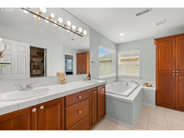 a spacious bathroom with a double vanity sink a bathtub a mirror and vanity