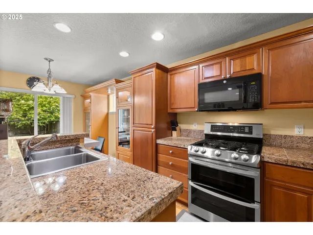 a kitchen with stainless steel appliances kitchen island granite countertop a stove top oven a sink dishwasher a dining table and chairs with wooden floor