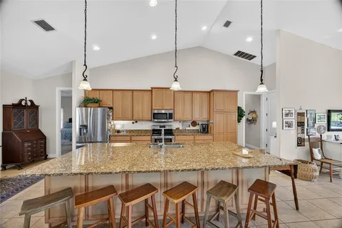 a kitchen with kitchen island granite countertop a table chairs sink and cabinets