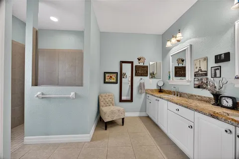 a large white bathroom with a double vanity sink a mirror and a bathtub
