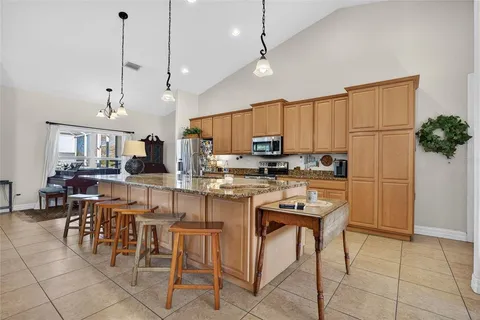a kitchen with stainless steel appliances kitchen island granite countertop a refrigerator a stove a microwave oven a sink with a dining table and chairs