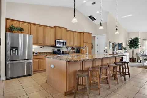 a kitchen with stainless steel appliances granite countertop a refrigerator a stove a sink a dining table and chairs