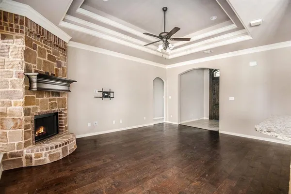 a view of an empty room with wooden floor and a fireplace