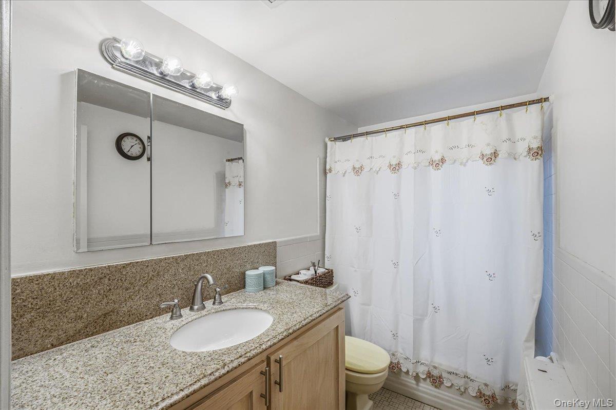 816 Pepperidge Road Westbury, NY 11590 - Photo 15 of 22 a bathroom with a granite countertop sink a toilet and a mirror