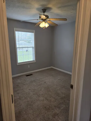 an empty room with a window and a fan