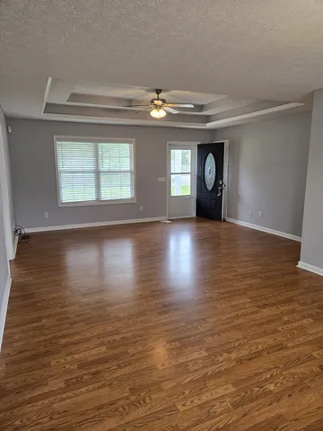 a view of an empty room with wooden floor fireplace and a window