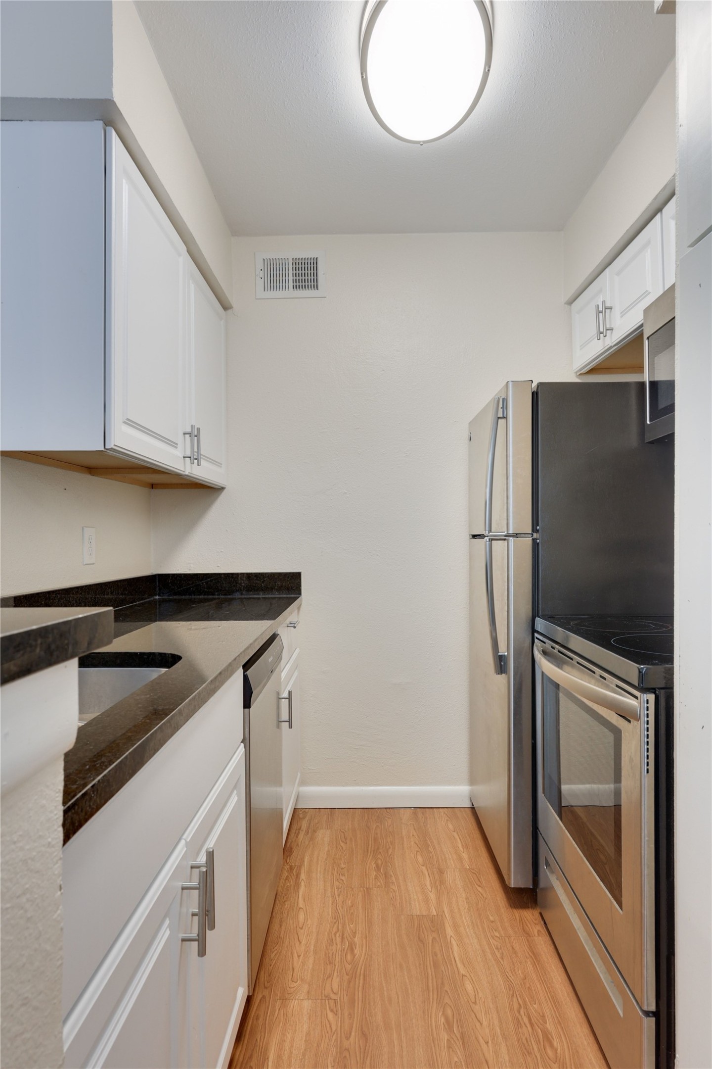 2207 Leon Street, Unit 204 Austin, TX 78705 - Photo 12 of 19 a kitchen with granite countertop a refrigerator and a stove top oven