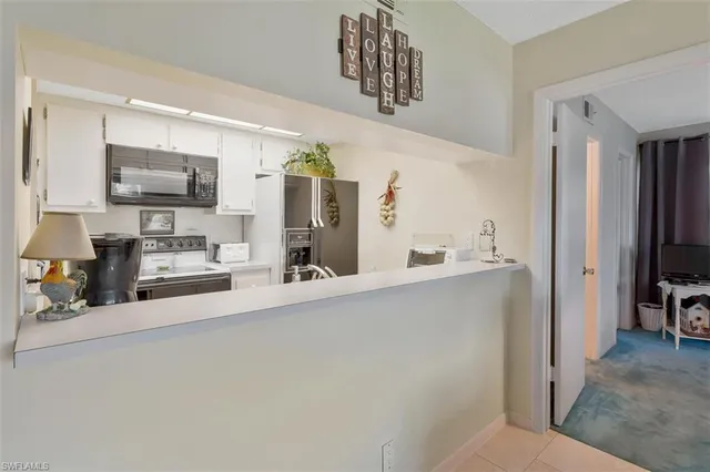 a living room with stainless steel appliances furniture a flat screen tv and a refrigerator