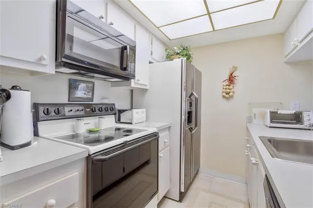 a kitchen with stainless steel appliances granite countertop a sink a stove a refrigerator and cabinets