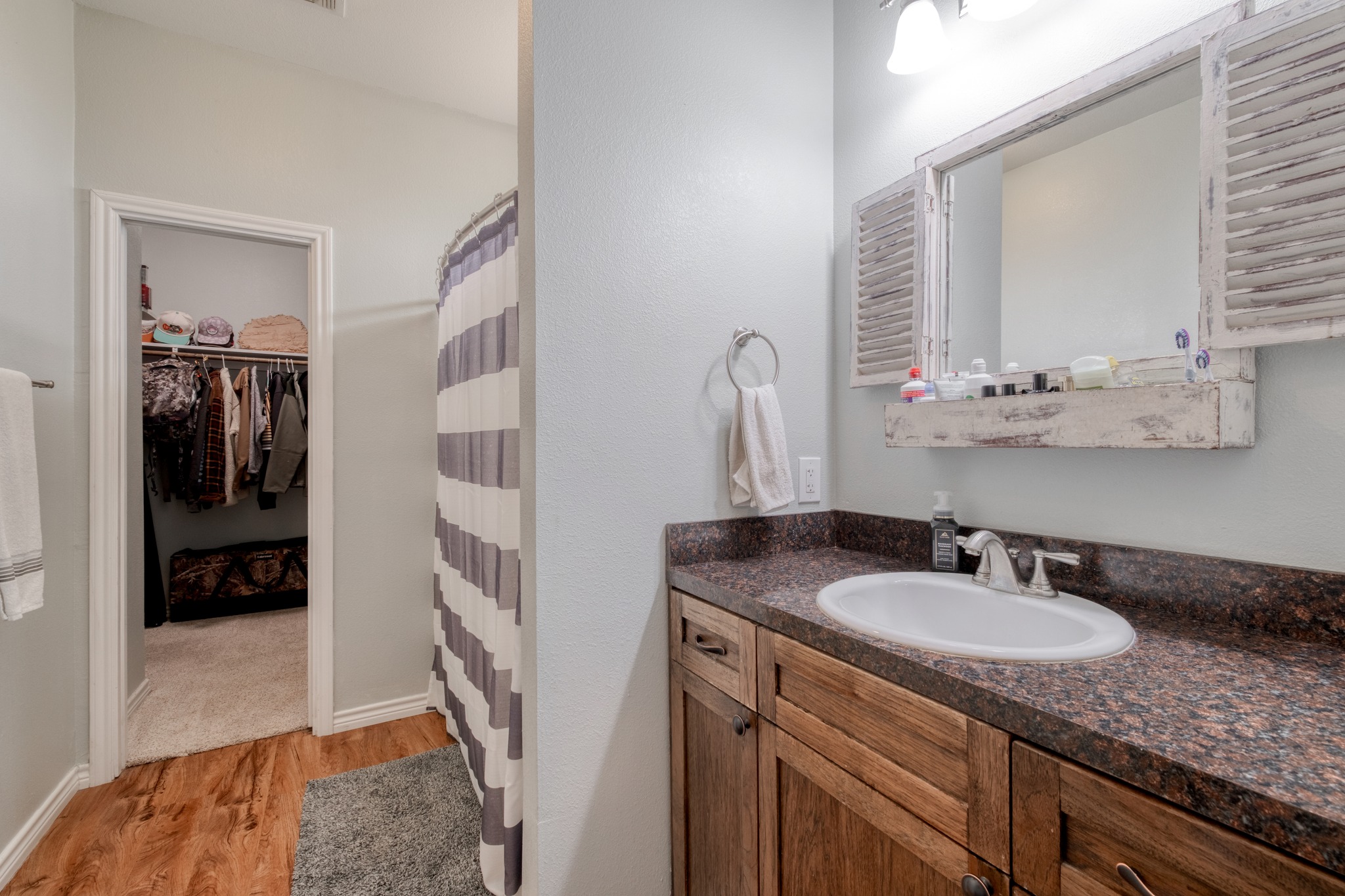 2950 County Road 484 Elgin, TX 78621 - Photo 15 of 25 Bathroom featuring vanity, a shower with shower curtain, light wood-style floors, and a walk in closet