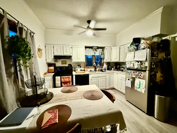 a kitchen with stainless steel appliances kitchen island granite countertop a refrigerator a stove and white cabinets with wooden floor