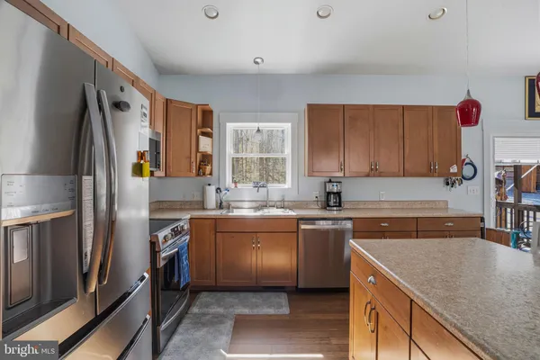 a kitchen with stainless steel appliances granite countertop a stove top oven a dining table and chairs with wooden floor