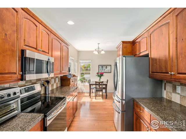 a kitchen with stainless steel appliances granite countertop a refrigerator stove oven dining table and chairs