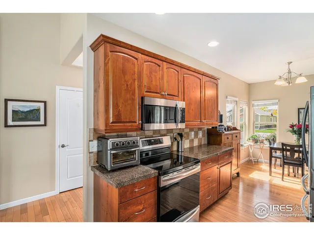 a kitchen with stainless steel appliances granite countertop a stove top oven a sink dishwasher a dining table and chairs with wooden floor