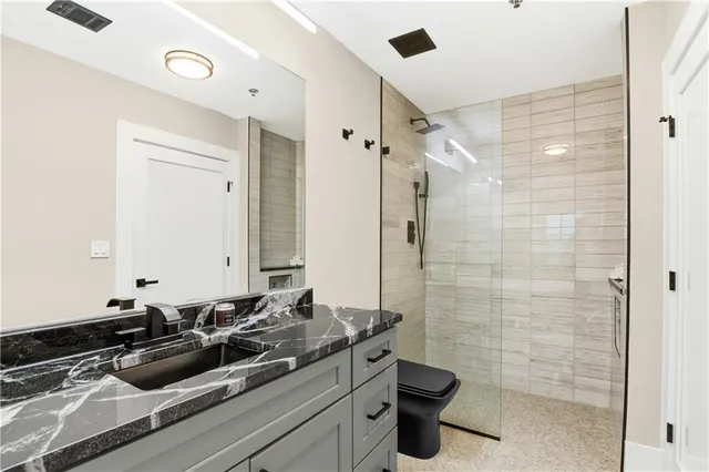 a bathroom with a sink a toilet a mirror and shower