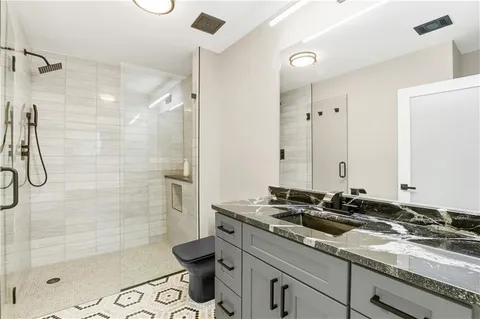a bathroom with a granite countertop sink a toilet and shower