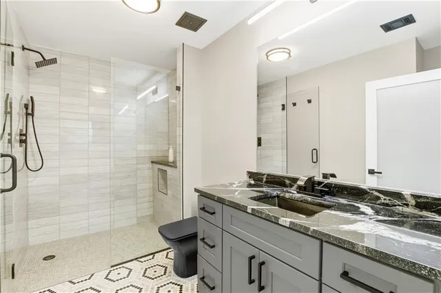 a bathroom with a granite countertop sink a toilet and shower