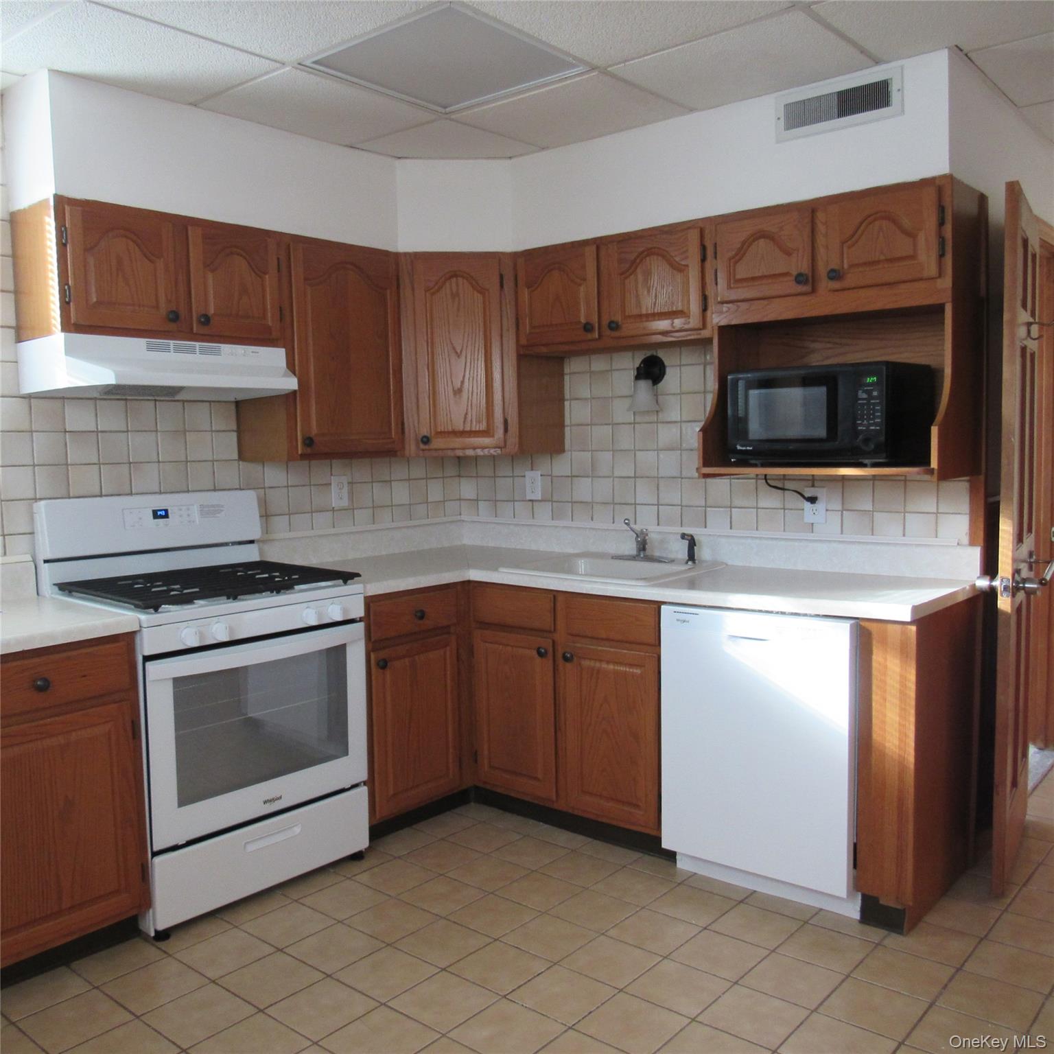 35 Taylor Avenue, Unit 2 Poughkeepsie, NY 12601 - Photo 5 of 19 Kitchen with white appliances, brown cabinets, light countertops, under cabinet range hood, and a microwave